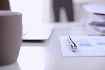 .Office workplace with a laptop and financial documents on the light reflecting table