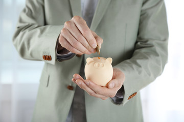 Man putting coin into piggy bank closeup