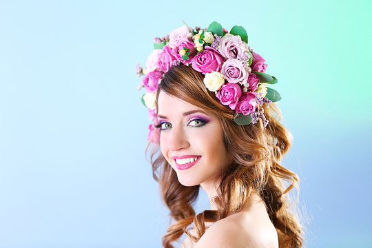 Beautiful young woman wearing floral headband on a blue background