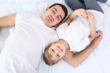 Obraz na płótnie Canvas Portrait of father and son in bed, top view