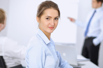 Obraz premium Beautiful business woman on the background of business people during meeting