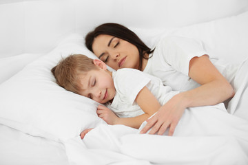 Mother and son sleeping in bed at home
