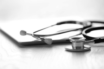 Stethoscope and tablet on wooden background