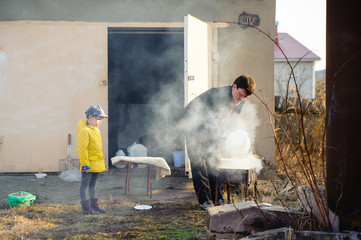 Man preparing barbecue on the grill with smoke and a little girl