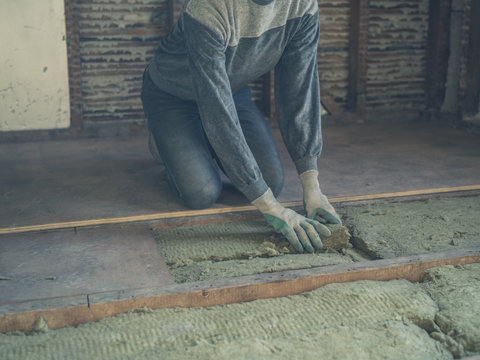 Young woman laying insulation in loft