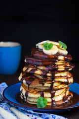 stack of pancakes with chocolate topping and banana