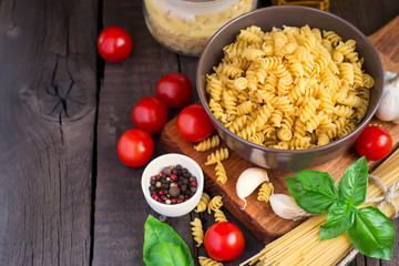 Pasta, herbsl and cherry tomatoes on old wooden background. Conc