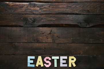 Easter folded paper origami colorful lettering on dark barn wood rustic planks background. Space for text, copy. Postcard template.