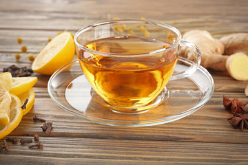 Cup of tea with ginger and cinnamon on wooden background