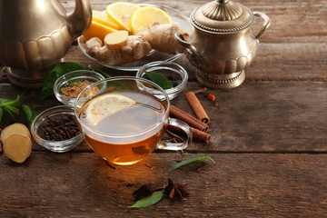 Cup of tea with ginger and cinnamon on wooden background
