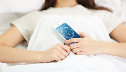 Young girl lying with her phone in the bedroom.