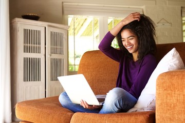 Portrait of a smiling female student sitting at home working on laptop
