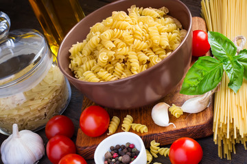 Raw pasta of different species, spice, cherry tomatoes. Concept