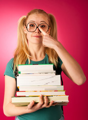 Curious, naughty, playful schoolgirl with stack of books and big