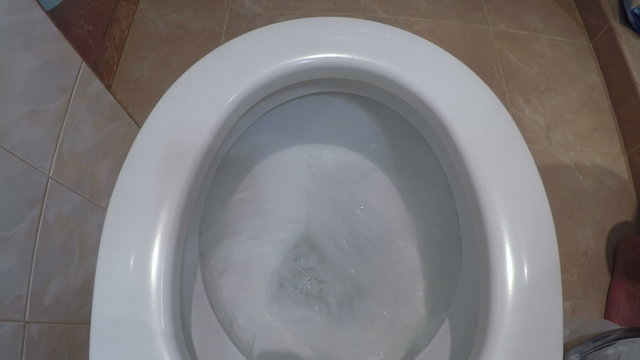 Top view of water flushing down into the toilet bowl in bathroom