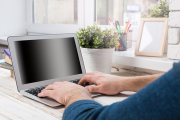 Man's hands using laptop with blank screen 