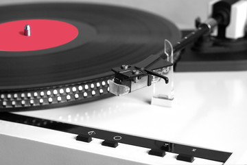 Fototapeta na wymiar Turntable in silver case playing a vinyl record with red label. Horizontal photo isolated on black background closeup