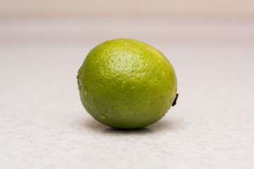 Ripe green lime with water drops on the kitchen table 