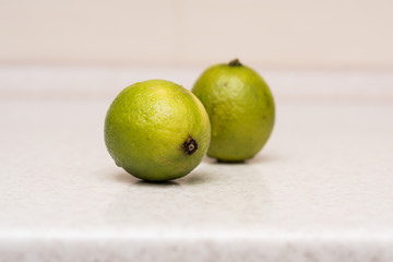 Couple of ripe green limes with water drops on the kitchen table 