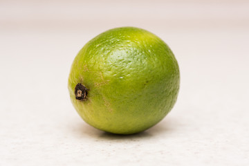 Ripe green lime with water drops on the kitchen table 