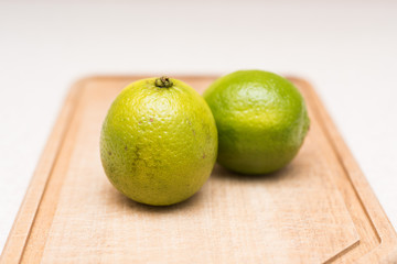 Couple of ripe green limes with water drops on the cut-board