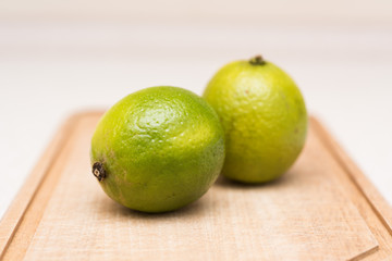 Couple of ripe green limes with water drops on the cut-board