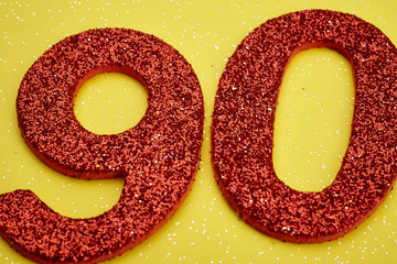 Number ninety red color over a yellow background. Anniversary