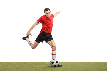 Obraz premium Young football player kicking a ball