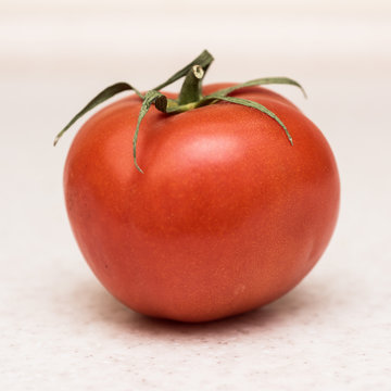 Ripe Red Tomato With Green Tassel On The Kitchen Table