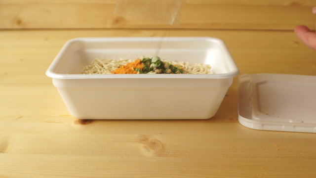 Female hand pour dried vegetables in instant noodles