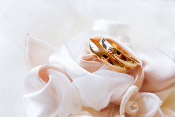 Golden wedding rings with diamond on silk fabric. Wedding jewelry details.