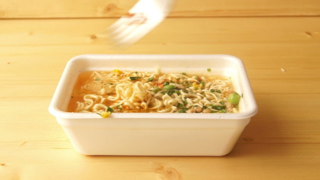 Someone stirs instant noodles with a fork