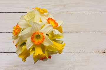 The bouquet of spring flowers yellow and white Narcissus on white wooden table. The view from the top. The Provence style, rustic. With space for text
