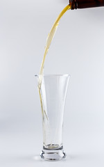 Pouring process of lager beer into a beer glass, splashes, drops and froth around glass