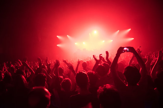 Applauding crowd at a live dj performance with red light