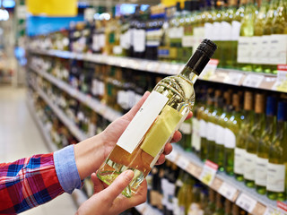 Woman with bottle of white wine in store