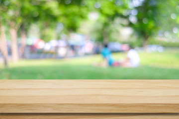 Empty wooden table over blurred park and people background