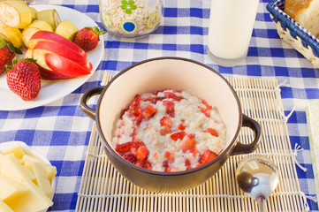 Still life breakfast of oat porridge with strawberries on a chec