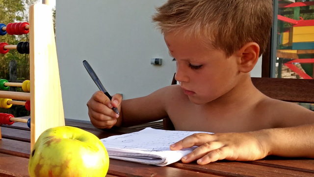 Little boy doing homework outside, zoom out