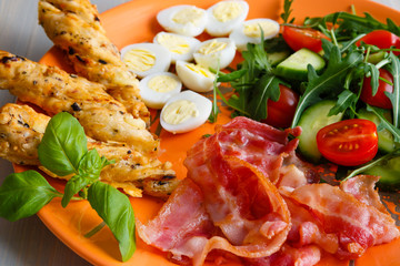 Traditional english breakfast egg, bacon, salad, homemade bread and basil