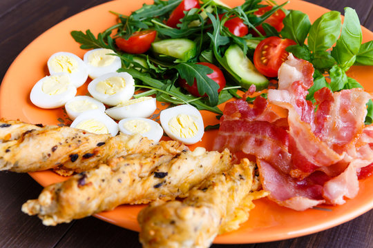 Healthy breakfast, bekon with salad and quail egg on orange dish