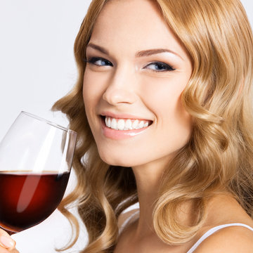 Young happy woman with glass of red wine, on gray