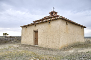 Fototapeta premium Old dovecote beside a tree in bloom, in the background one lagoon, located in Zamora, Spain