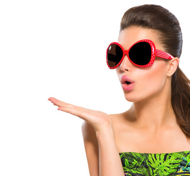 Fashion model girl wearing red sunglasses showing empty copyspace on open hand