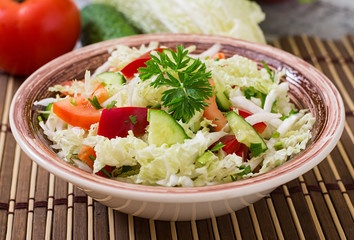 Dietary salad with fresh vegetables (cabbage, pepper, tomato, cucumber) in a ceramic bowl