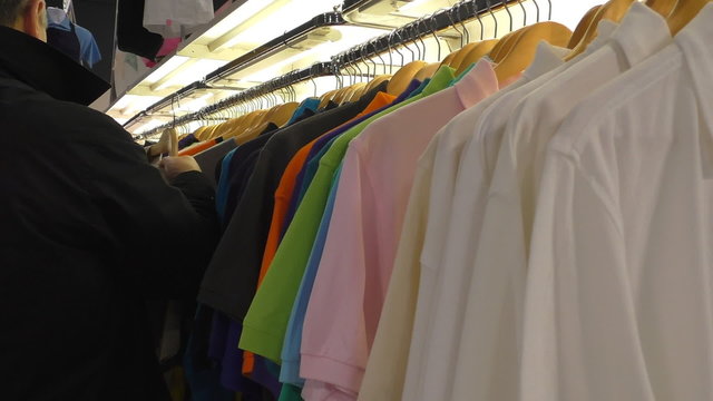 Man in black coat at the clothes shop choosing his favorite brand t shirt. 
