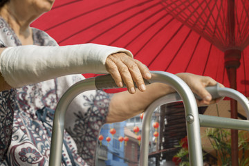 senior woman broken wrist using walker , isolated on white.