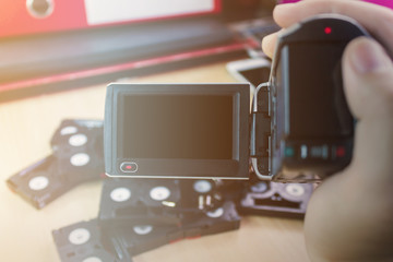 Hand and video camera recording cassette tapes in office backgro