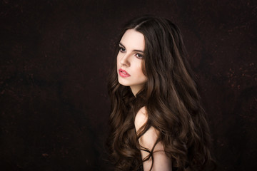 Fashionable portrait woman with long healthy shiny hair on a dark background.