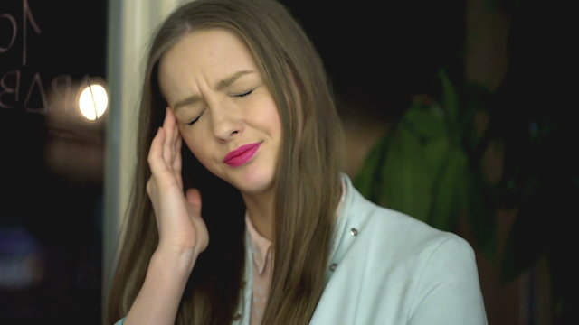 Girl taking off glasses and massage her head because of headache
